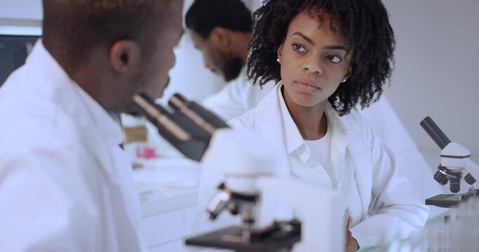 African ethnicity doctors working in laboratory. Studying human skeleton and virus models. Discussing, using microscope and computers