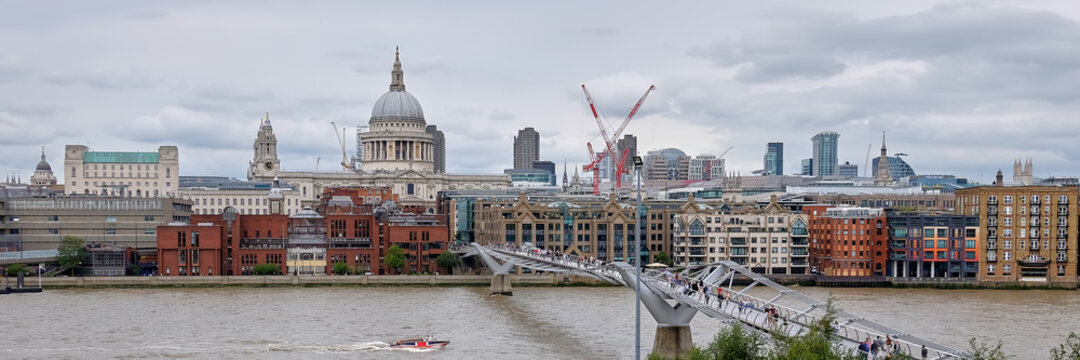 London, panoramic aerial view over Thames river with Millennium bridge, St. Paul and London skyline. Overcast day with grey sky and clouds. Toned image.