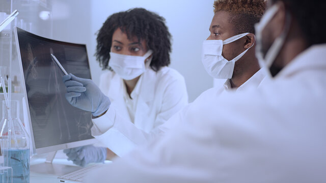 African ethnicity doctors working in laboratory. Studying human skeleton and virus models. Discussing, using microscope and computers