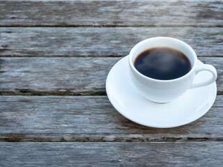 Top view of a hot aromatic brewed mug of black organic coffee on rustic and weathered wood palnk background.
