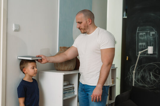 father measures sons height at home