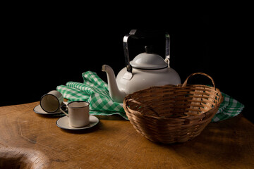 coffee table with cups, teapot and empty basket on rustic wood, low key portrait, selective focus.