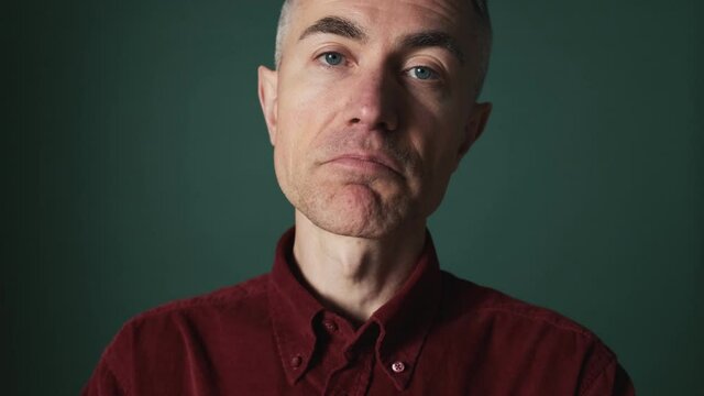 A close-up view of an emotional elder man is giving different answers yes while he agree and disagree with something standing isolated over green background in the studio