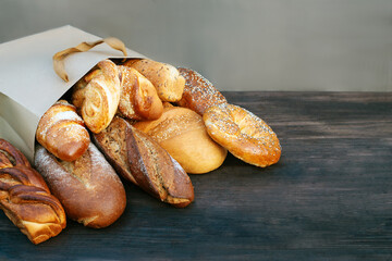 Package with bread and buns on a brown table on a picnic