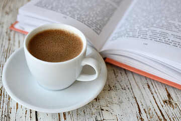 Сup of coffee and a book on table
