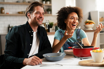 Boyfriend and girlfriend eating lunch with friends at home. Young couple enjoying the company of their friends.