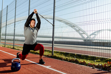 Fit man is training outside with various sport props. Workout in the morning near river.