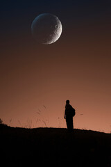 silhouette of a man watching the moon at night
