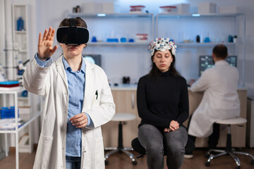 Obraz premium Professional researcher wearing virtual reality glasses using medical inovation in lab analysing brain scan of patient. Team of neurological doctors working with equipment high tech simulator device.