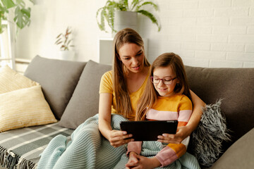 Mom is showing to her preschool daughter how to use tablets and how to play video games.