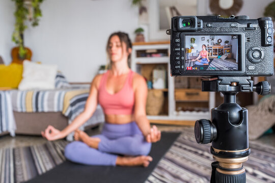 Young woman exercising at home doing pilates and recording at her with digital camera to teach workout and produce web class - content creator business free healthy lifestyle people concept