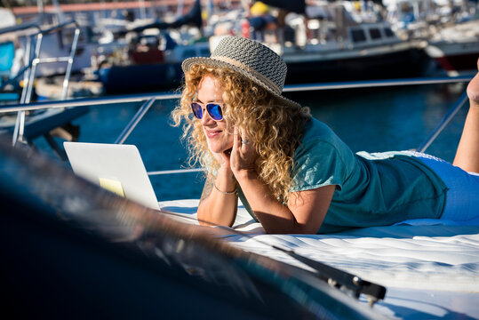 Woman smile laying on the deck of the boat in summer holiday vacation and watch laptop - concept of free lifestyle modern pretty female people - computer technology outdoor connection - Powered by Adobe