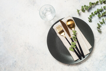 Table setting with white plate, cutlery and eucalyptus .