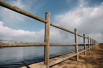 Obraz premium Wooden fence made of logs at a lake.