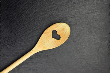 Wooden spoon on slate stone background, in dark color, copy space