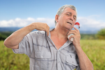 Elderly man touching face with bottle as hot summer concept