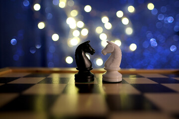 chess pieces, horse, white and black on a chessboard, concept of leadership and teamwork in...
