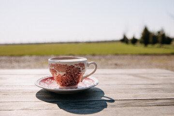 Vintage cup of coffee on a wooden table at a terrace, outdoors in the backyard.