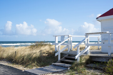 Beach entrance in Kühlungsborn with blue sky on a sunny day with white wooden railings,...