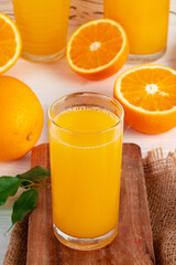 Glass of orange juice and cut oranges on table