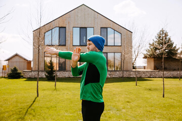 Naklejka premium Man working out outdoors in the morning in backyard at home. Man stretching arms.