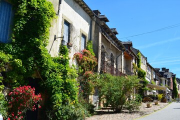 The narrow and picturesque alleys of Najac. Old stone houses decorated with flowers. South France. 