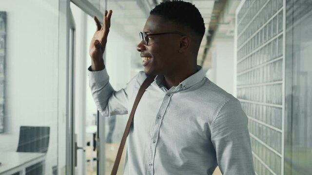 A happy american guy is walking down the hall inside the office building