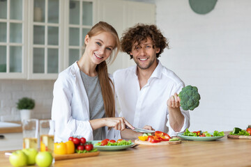 Happy young couple have fun in the kitchen while preparing fresh vegetables. Healthy and food.