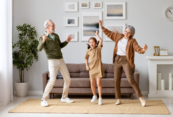 Excited preschool girl having fun with active positive grandparents