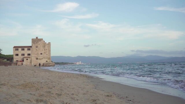 Middle Age tower by the mediterranean sea with man and dog, Torre Mozza, Italy