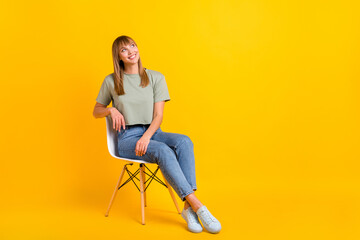 Fototapeta na wymiar Portrait of charming cheerful girl sitting in office chair deciding making solution isolated over bright yellow color background