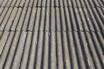 Gray aged dry roofing slate roof - vertical old asbestos profile texture background in perspetive close up, village style