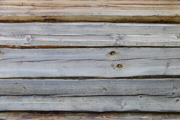 Old weathered Russian log cabin rural house wall grey wooden logs horizontal texture for background