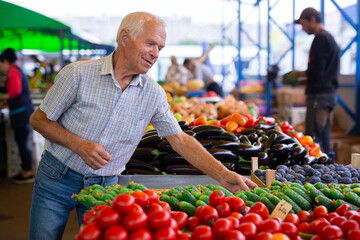 retired european man buying tomatoes in market