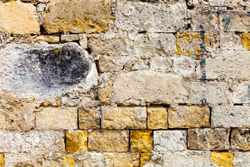 Worn grunge ruined surface bricks wall. Concrete material. An old grungy and dirty concrete wall with yellow bricks. Surface ruined facade.