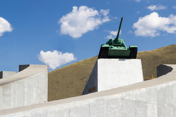 The Soviet tank installed on the top of the with blue sky white clouds and green hill