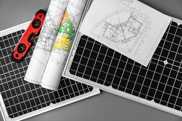 Architectural blueprints and solar panel on table