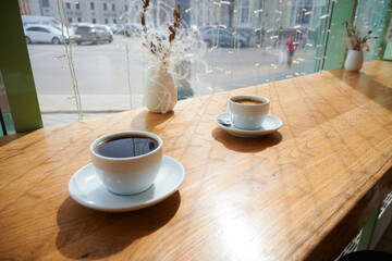 Two mugs of coffee on a sunny wooden table