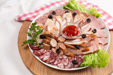 Meat plate with different types of sausage and prosciutto with olives and rosemary.