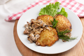 Potato pancakes in white mushroom sauce. Draniki - potato fritters. Potato pancakes on white background.