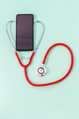 Fototapeta na wymiar Top view of a red stethoscope with stethoscope headphones on a green background. Medical and communications concept or cell phone repair.