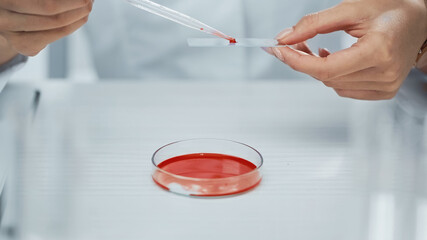 partial view of african american scientist taking blood from test plate with pipette