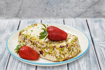Halva with pistachios and strawberries on wooden boards