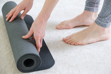 Woman hands rolling up yoga exercise mat
