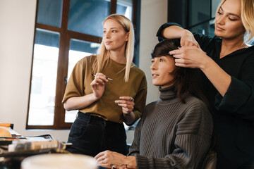 Young two women doing hairstyle and makeup for their client
