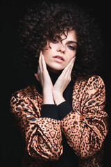 Fashionable portrait of a white Caucasian girl with African curls. Girl in a leopard-print jacket on a black background.