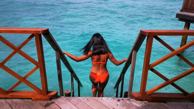 Beautiful slim woman in a bikini in a water villa in the Maldives