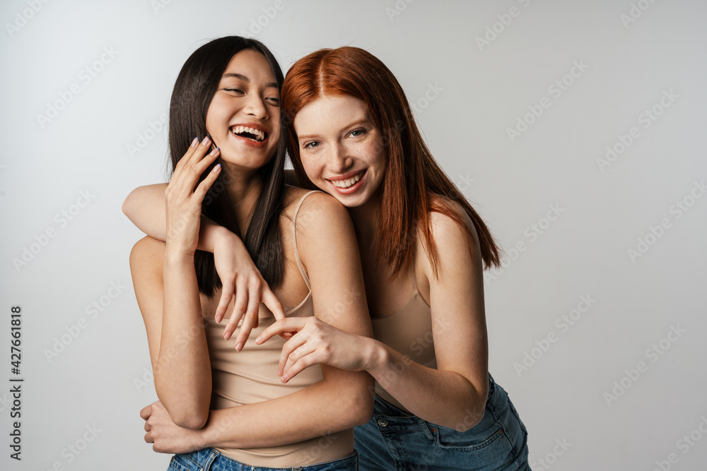 Wall mural multiracial two women hugging and laughing at camera