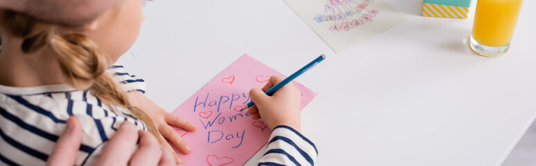 partial view of man touching shoulder of daughter drawing happy womens day card, blurred foreground, banner