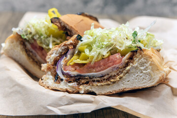 Vegan sandwich is loaded between baked bread with fried eggplant, provolone cheese, mayo, and vinaigrette to fill any appetite.